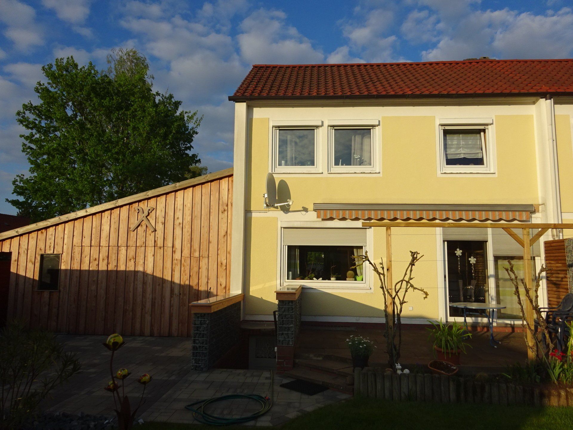 Ein gelbes Haus mit einem roten Dach und einem Holzzaun