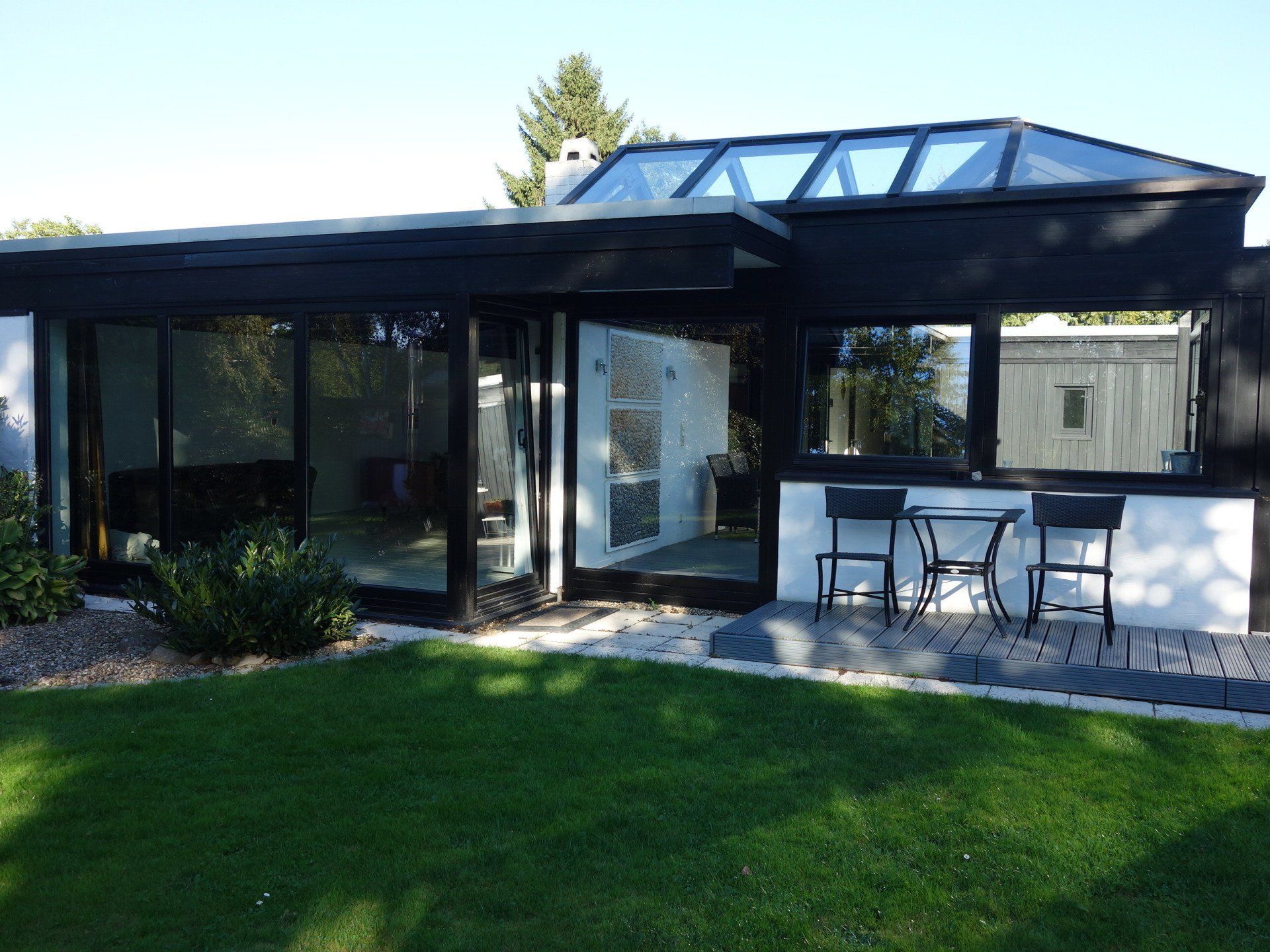 Ein Haus mit vielen Fenstern und einem Tisch und Stühlen davor.