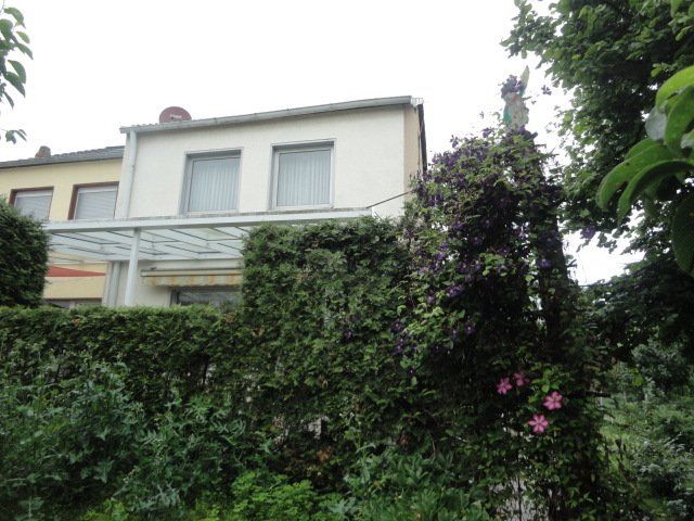 Ein Haus mit Glasdach ist von Bäumen und Büschen umgeben