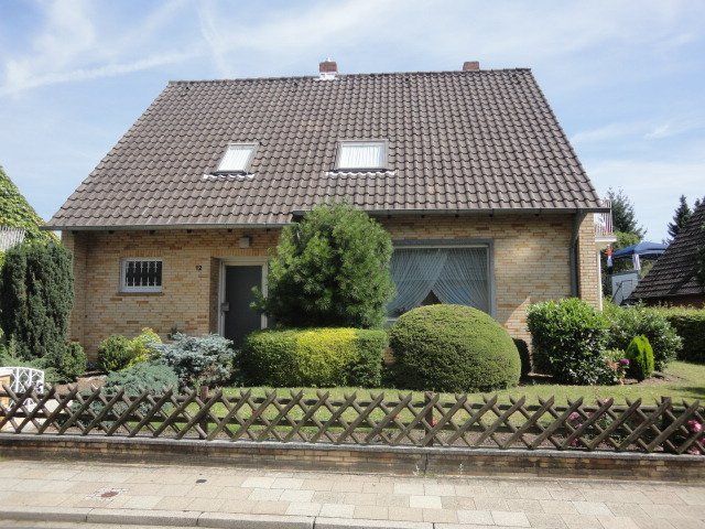 Ein Backsteinhaus mit einem braunen Dach und einem Zaun davor