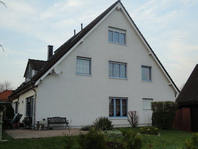 Ein weißes Haus mit einer Bank davor