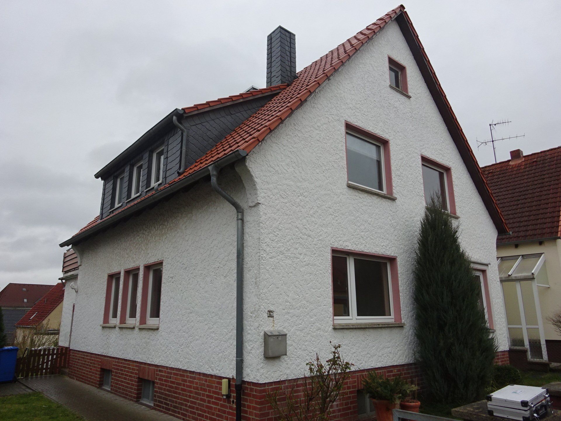 Ein weißes Haus mit einem roten Dach und einem Baum davor