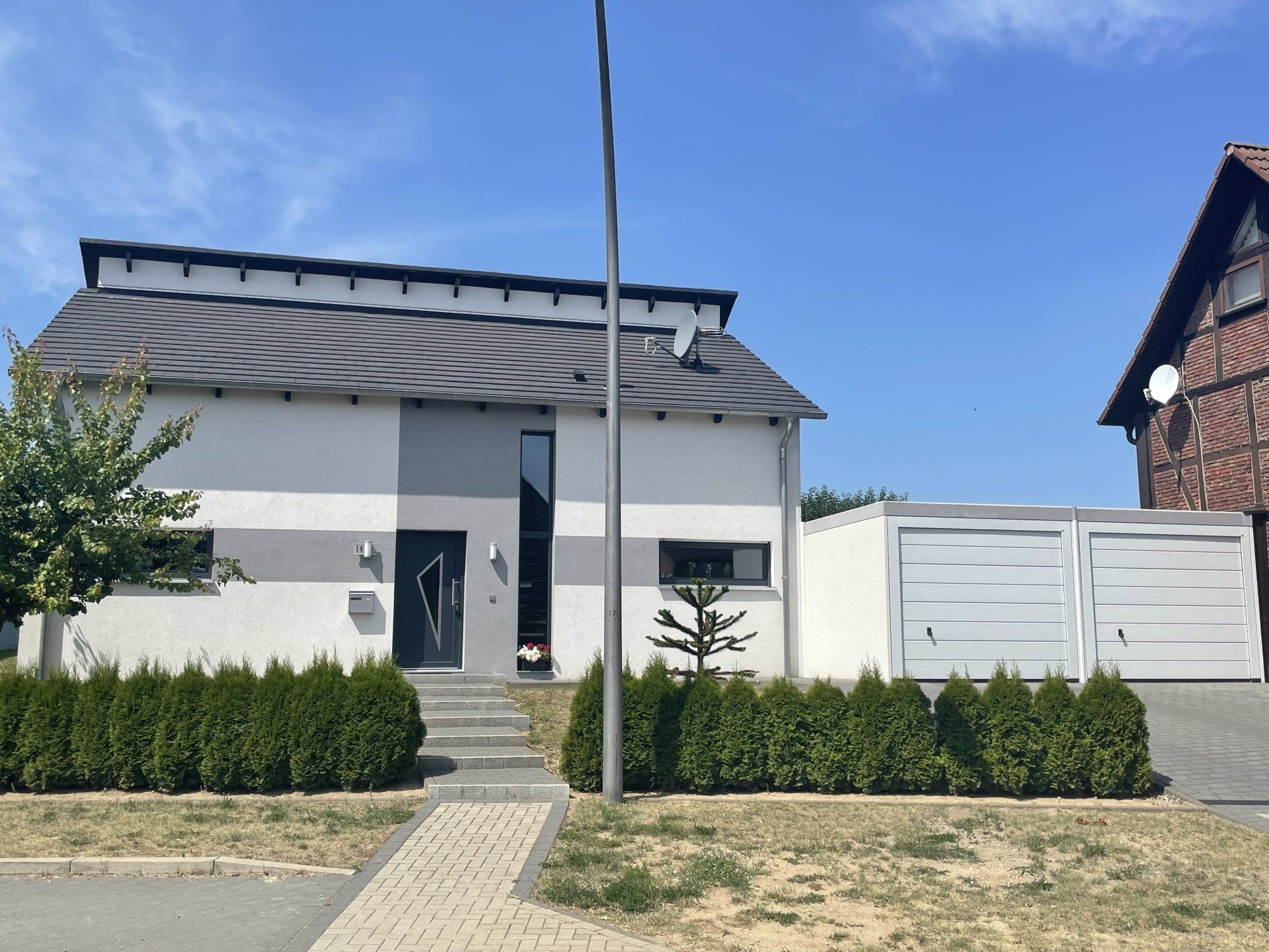 Ein weißes Haus mit grauem Dach und einer Garage