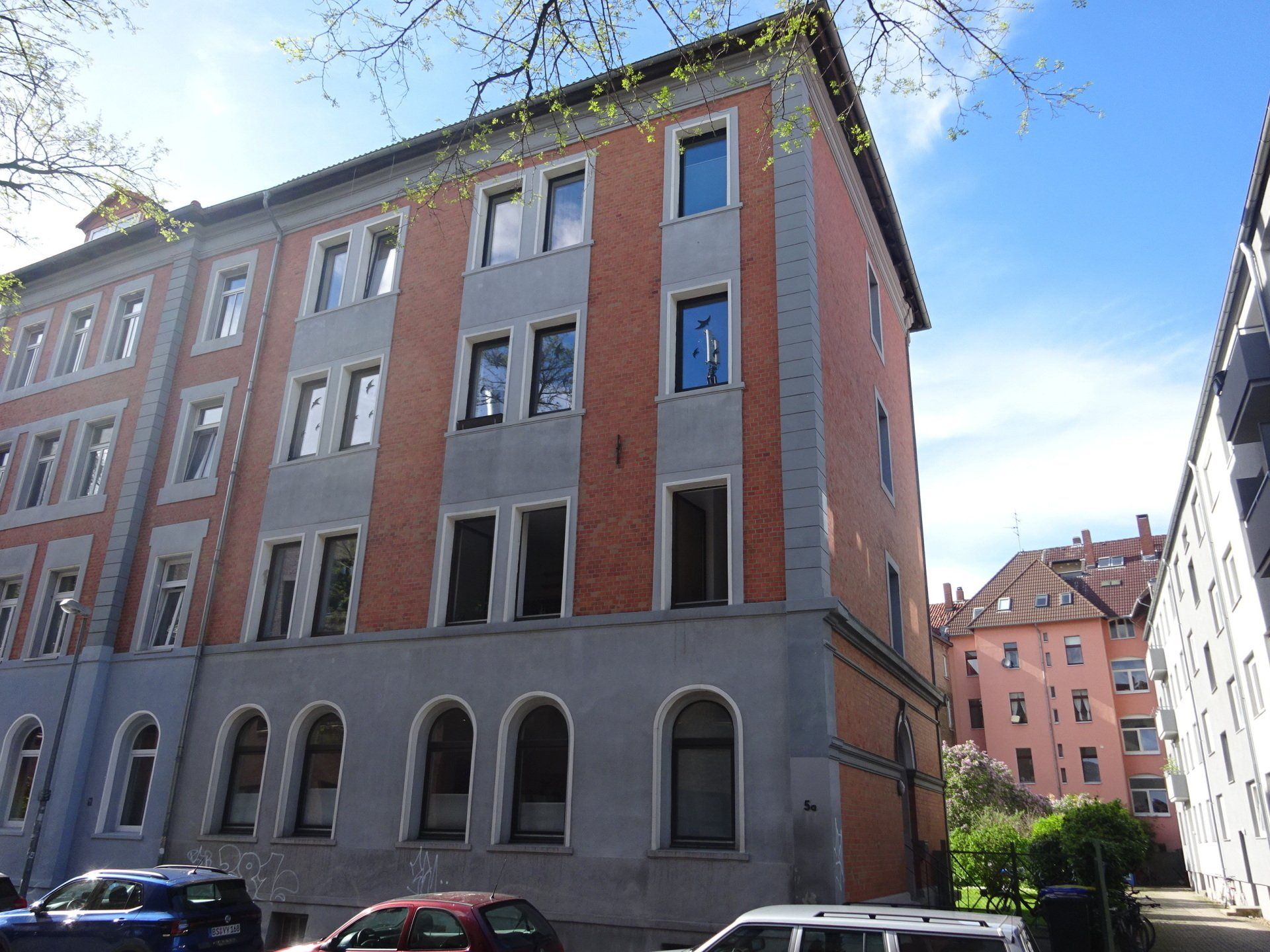 Ein großes Backsteingebäude mit davor geparkten Autos