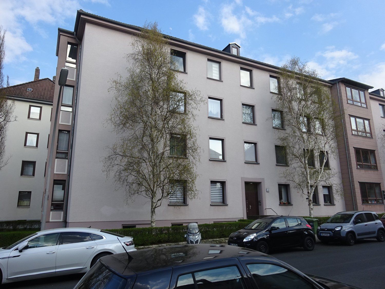 Ein Gebäude mit vielen Fenstern und davor geparkten Autos