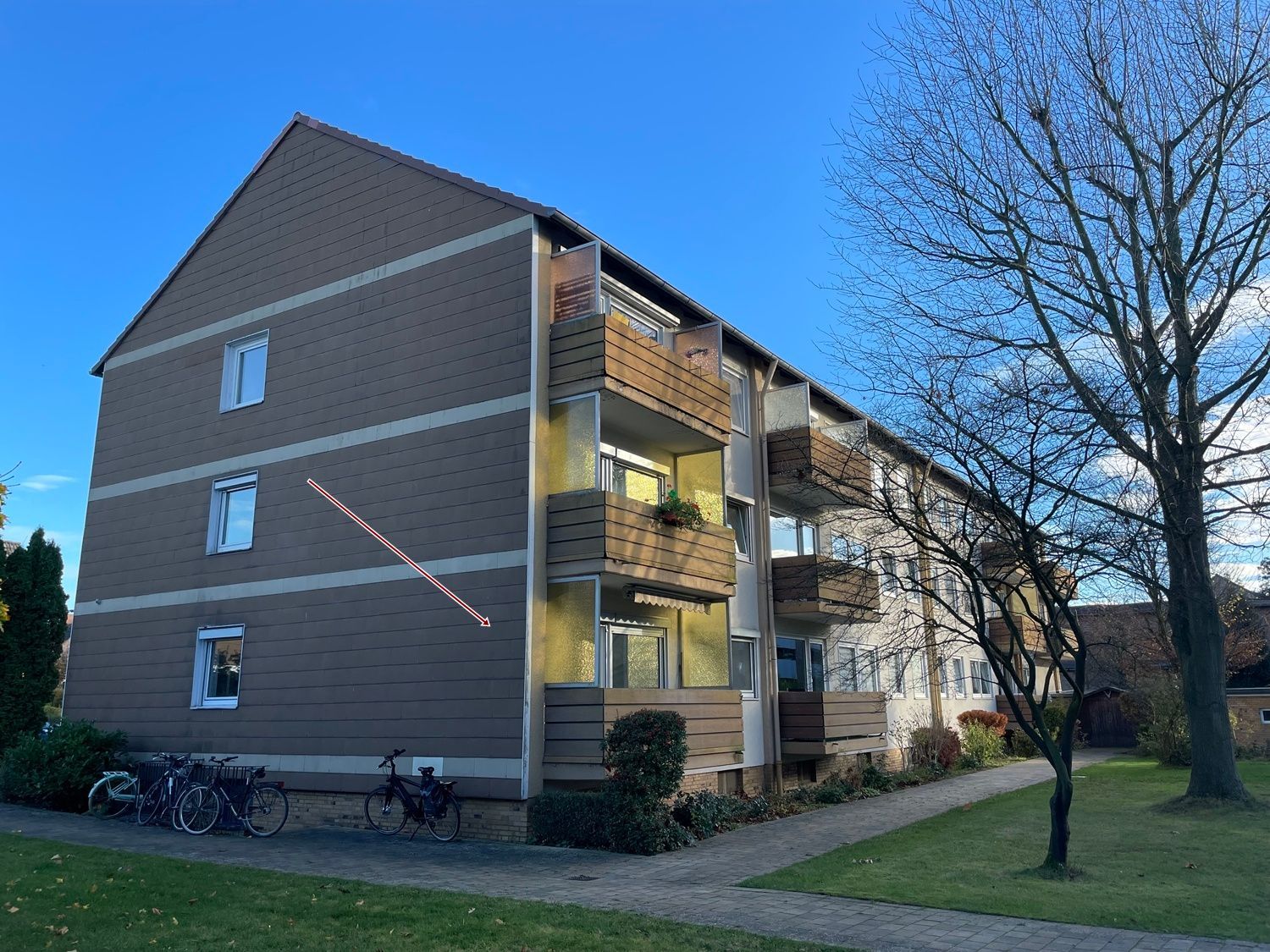 Ein großes Mehrfamilienhaus mit vielen Balkonen und davor geparkten Fahrrädern.