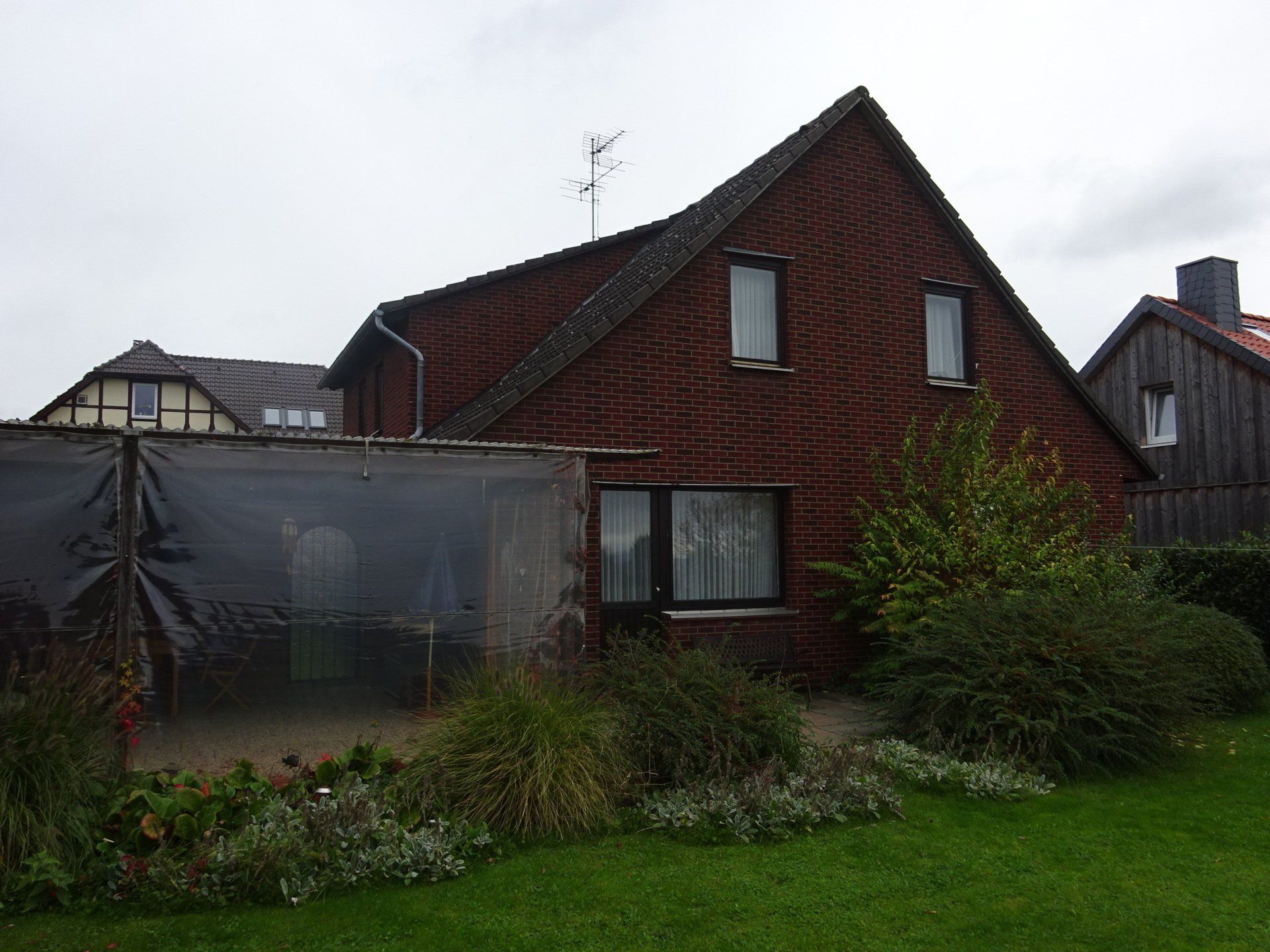 Ein Backsteinhaus mit einem Gewächshaus davor.