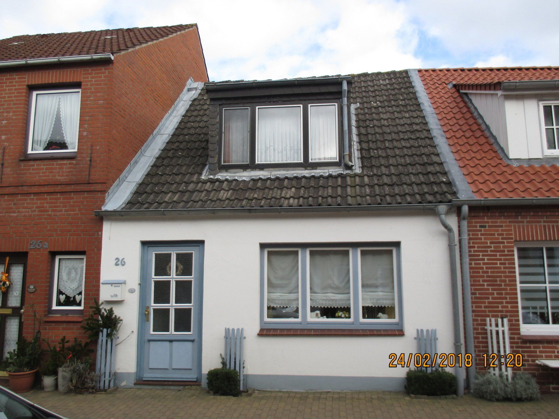 Ein weißes Haus mit einer blauen Tür steht neben einem roten Backsteinhaus