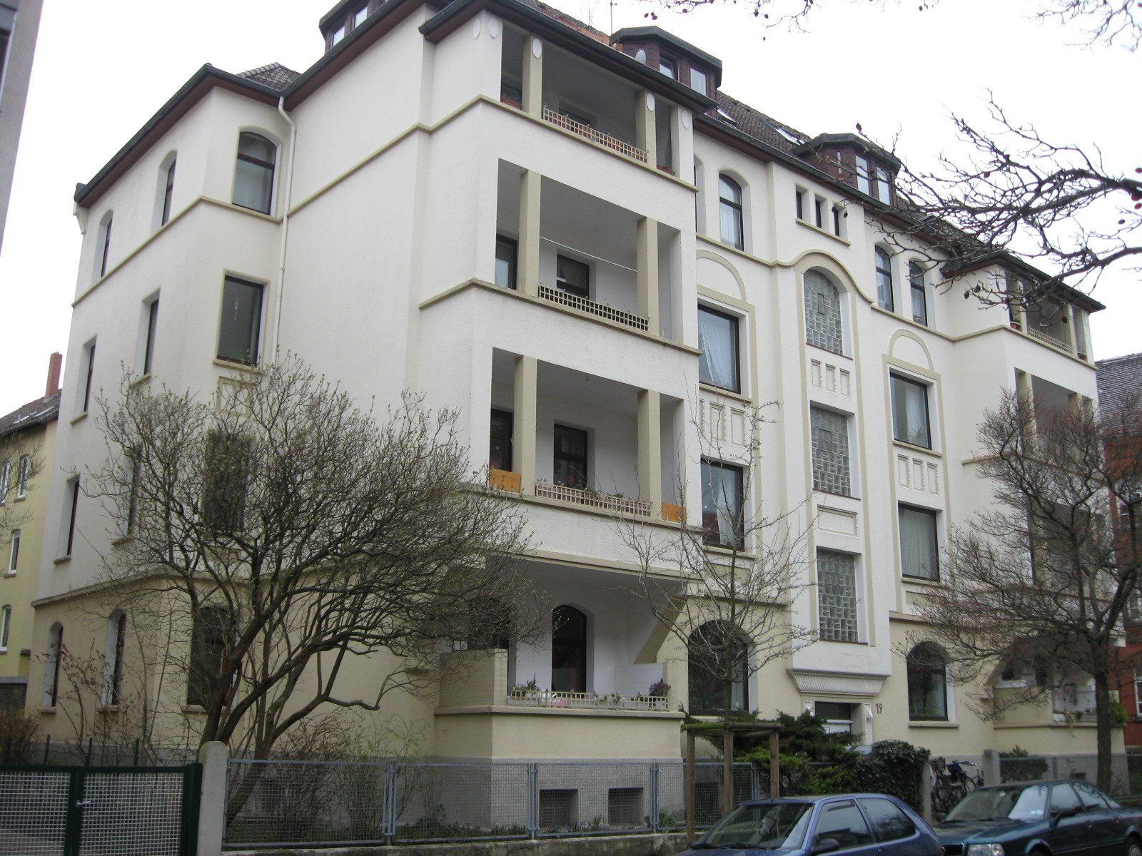 Ein großes weißes Gebäude mit davor geparkten Autos