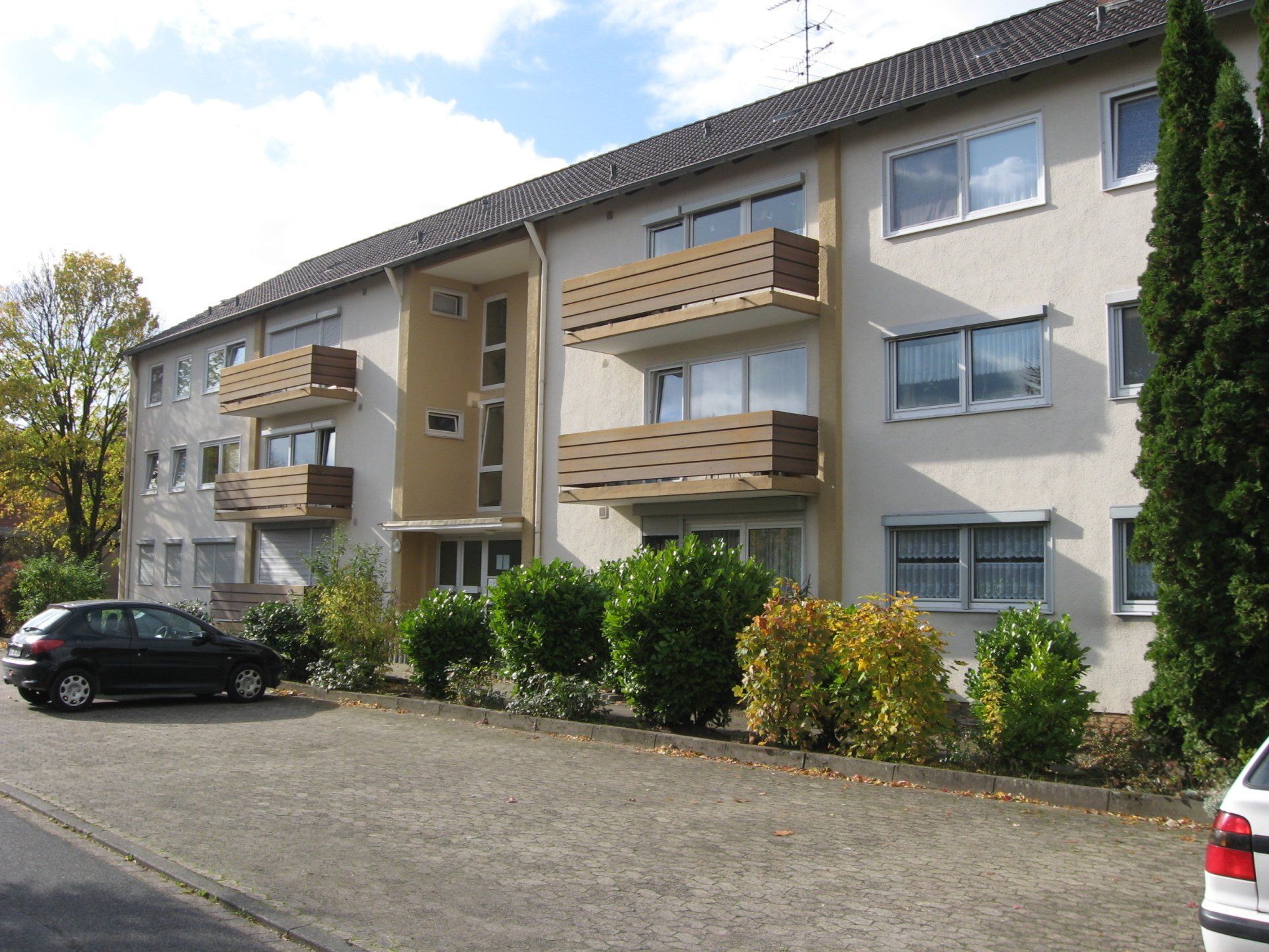 Ein Auto ist vor einem Gebäude mit Balkonen geparkt