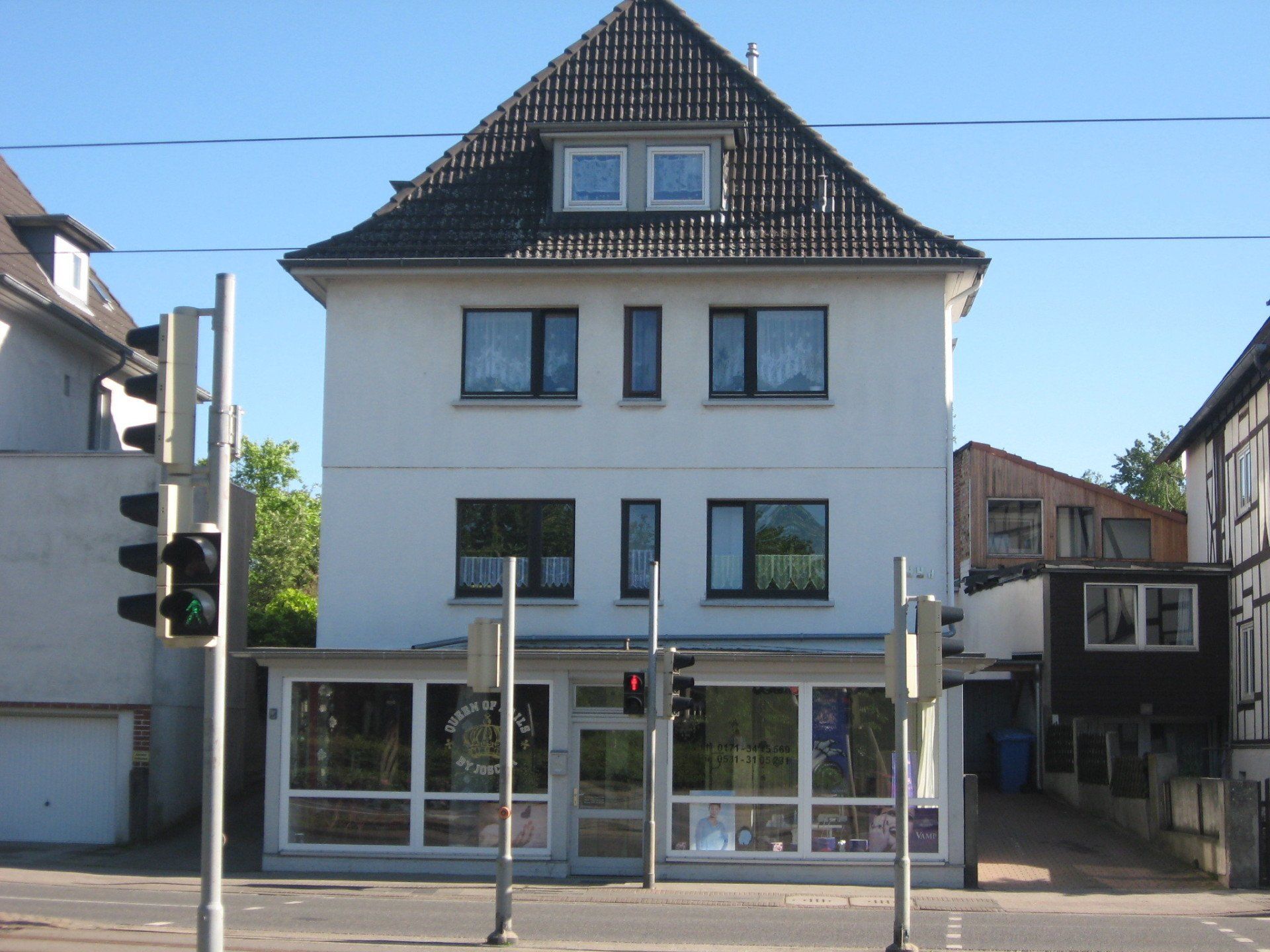 Ein weißes Gebäude mit einem schwarzen Dach steht an der Ecke einer Straße