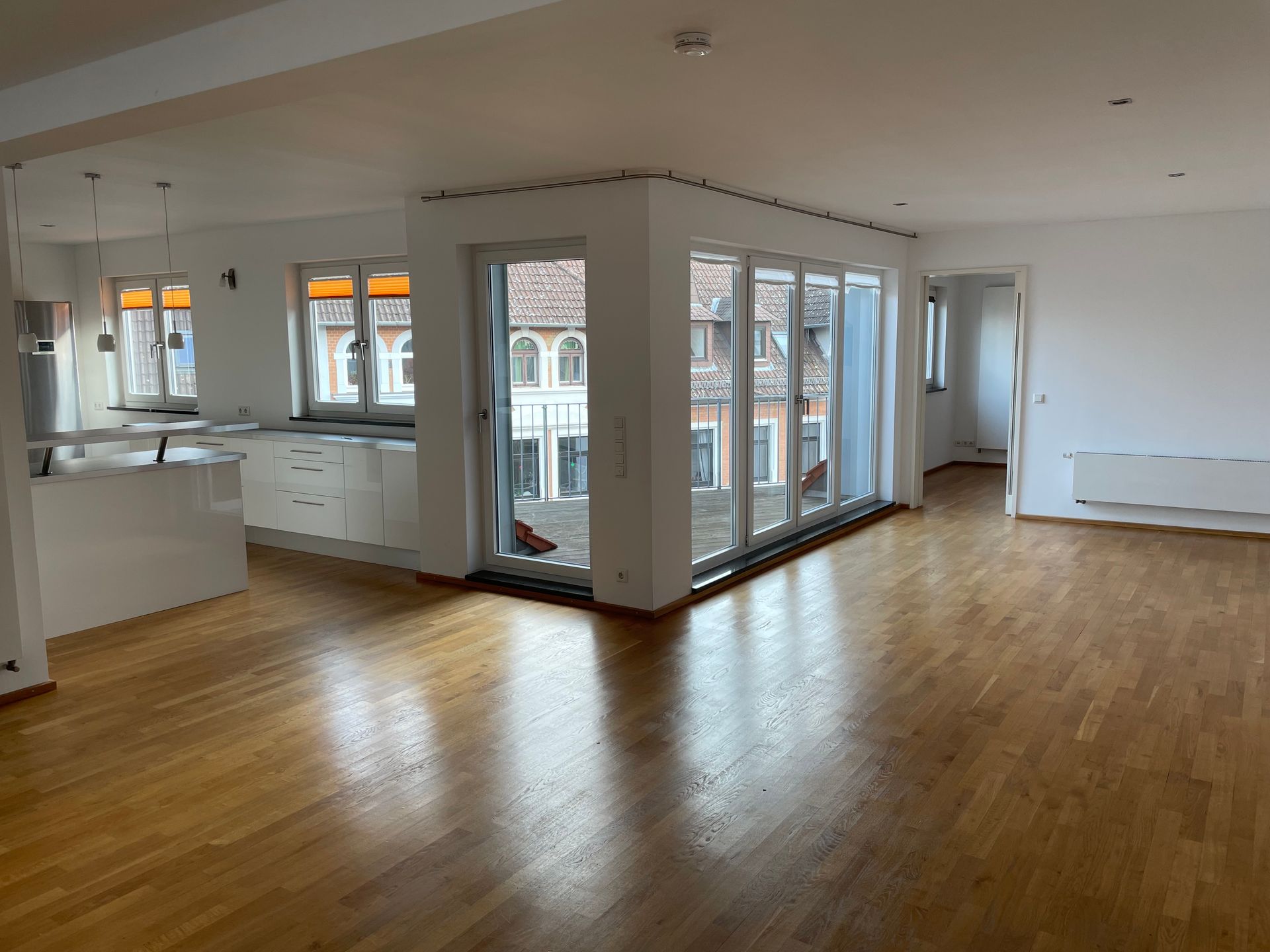 Ein großer leerer Raum mit Hartholzböden und vielen Fenstern.