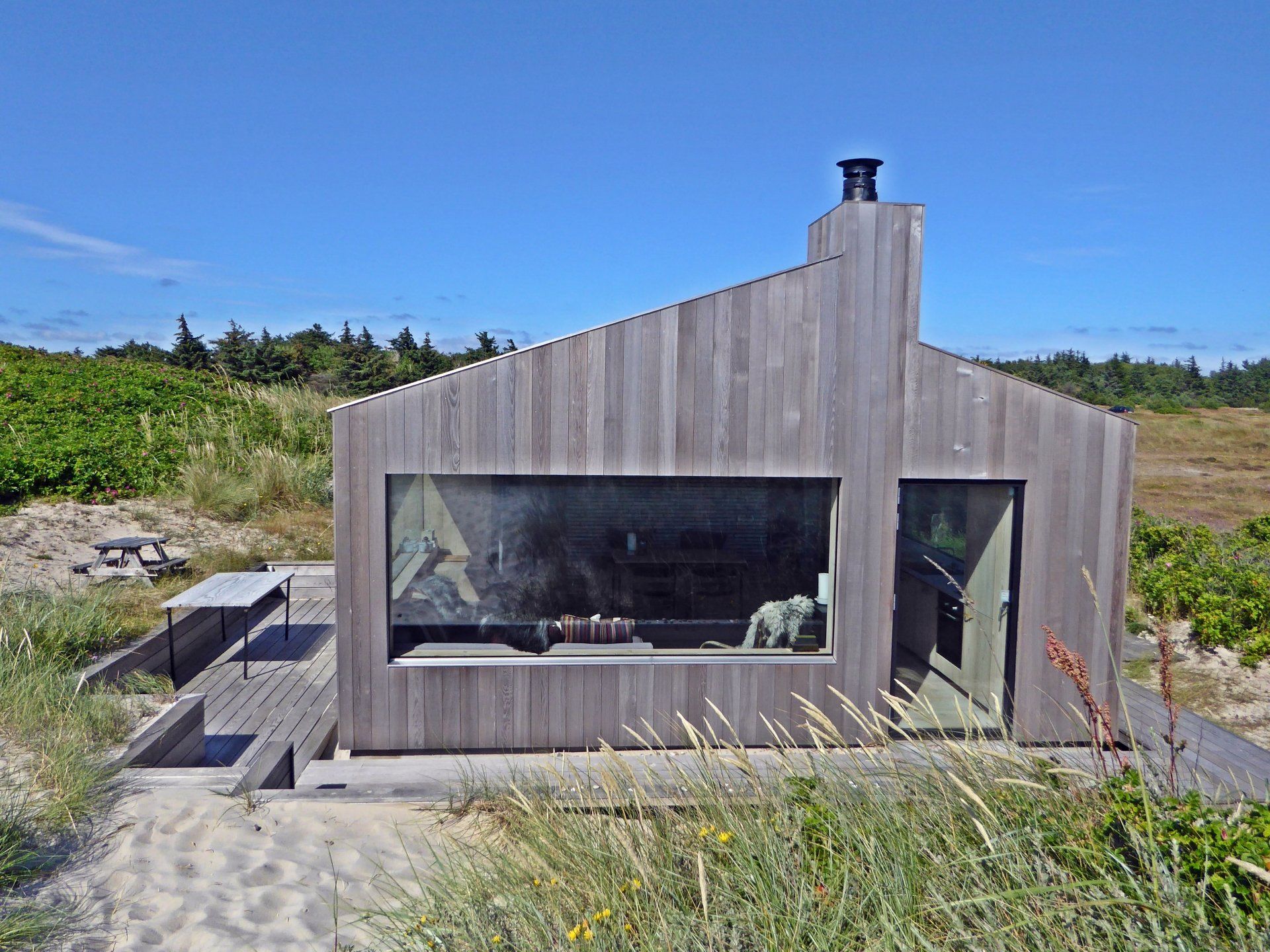 Ein kleines Holzhaus mit einem großen Fenster mitten auf einem Feld.
