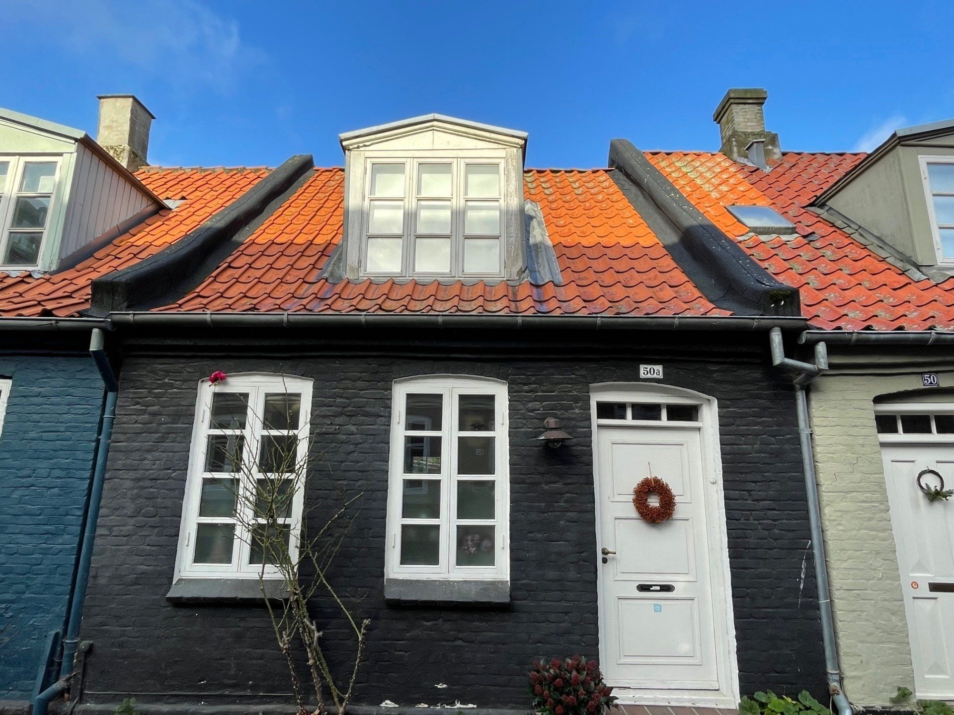 Ein schwarzes Haus mit einer weißen Tür und einem roten Dach