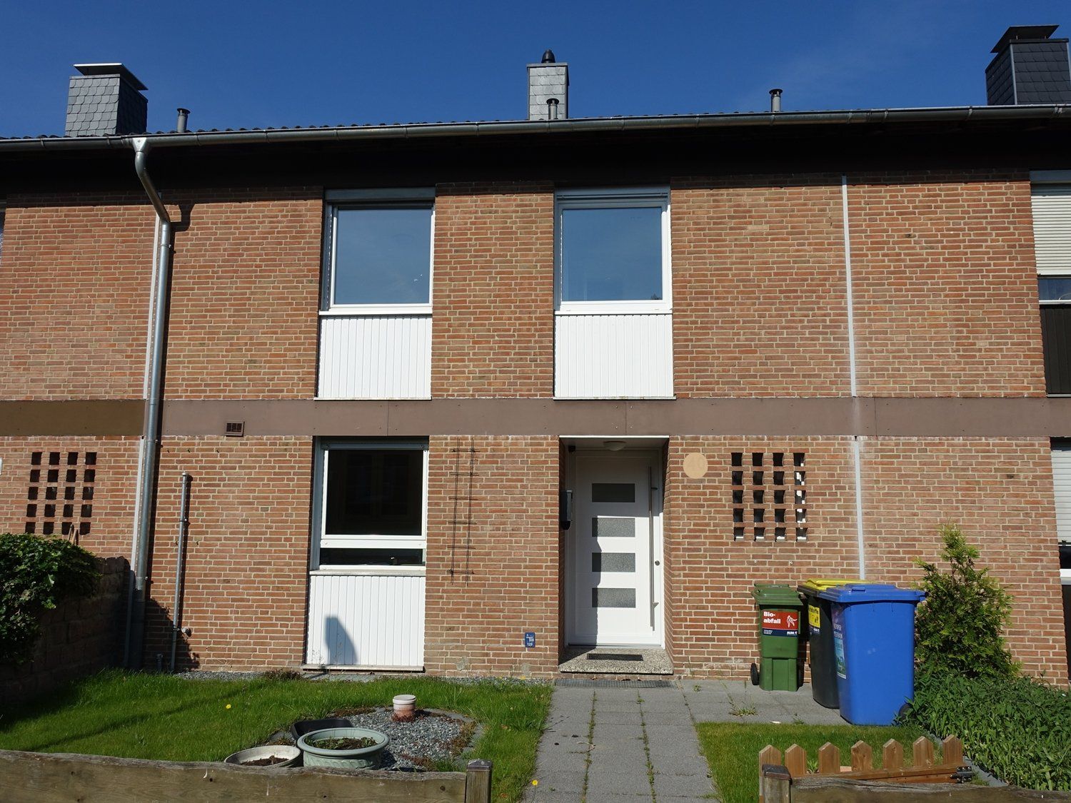 Ein Backsteinhaus mit einer weißen Tür und weißen Fenstern