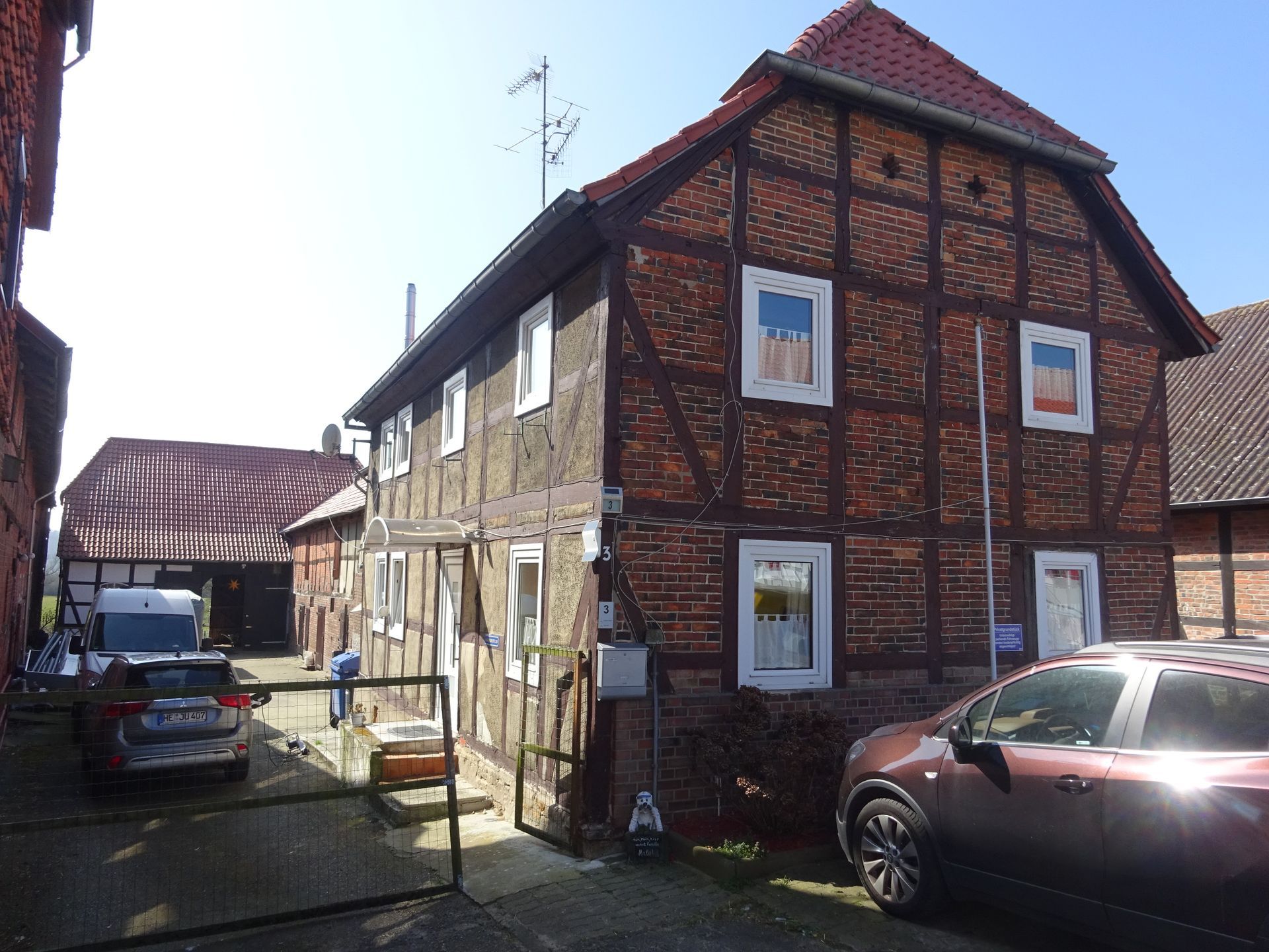 Vor einem Backsteingebäude parkt ein rotes Auto.