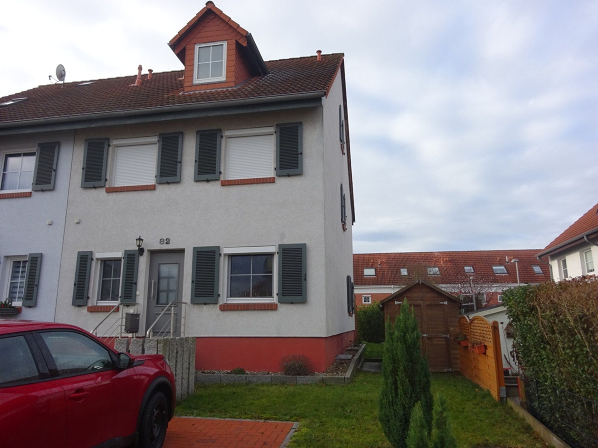 Ein rotes Auto steht vor einem weißen Haus