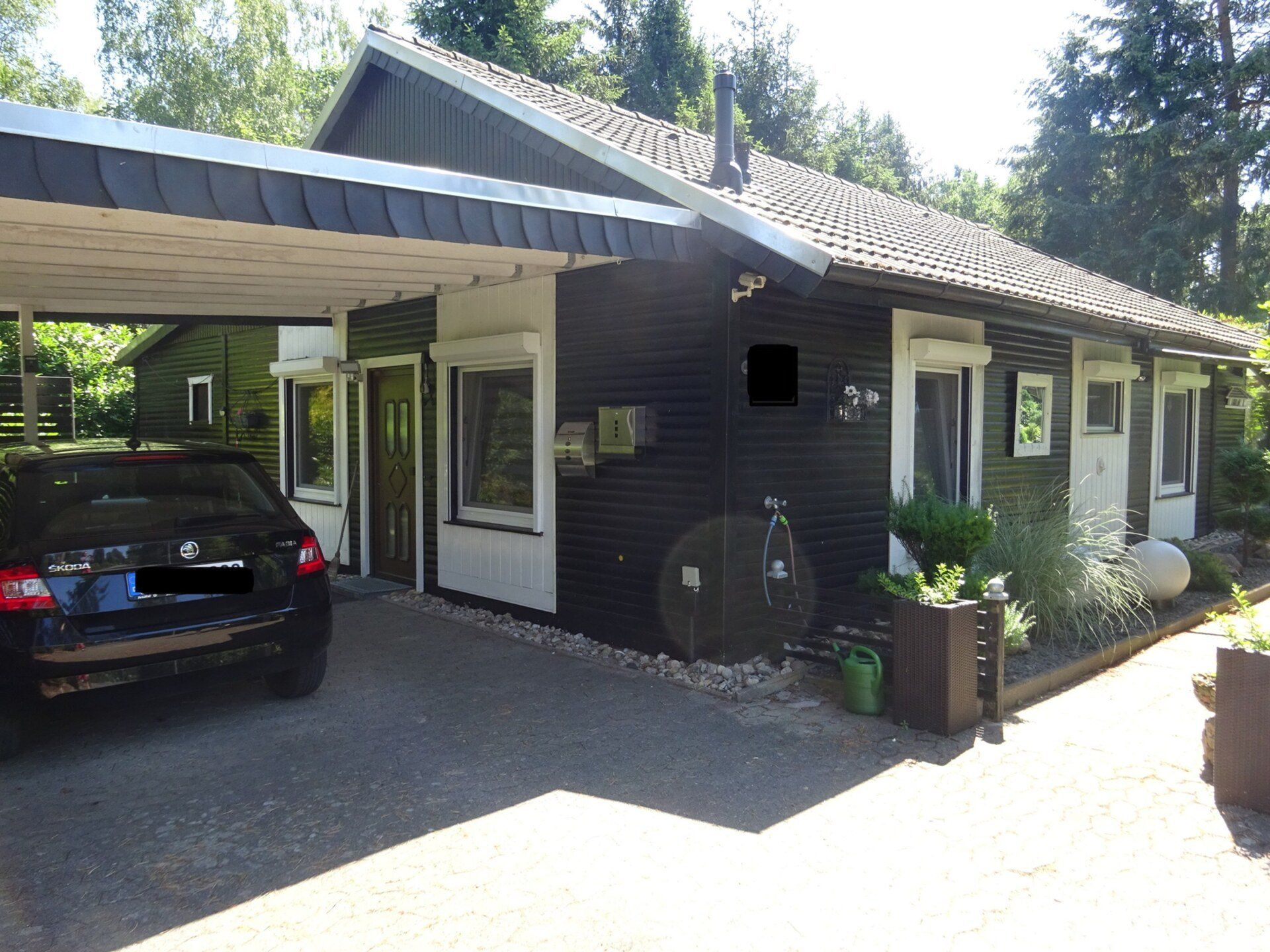 Ein Auto ist unter einem Carport vor einem Haus geparkt