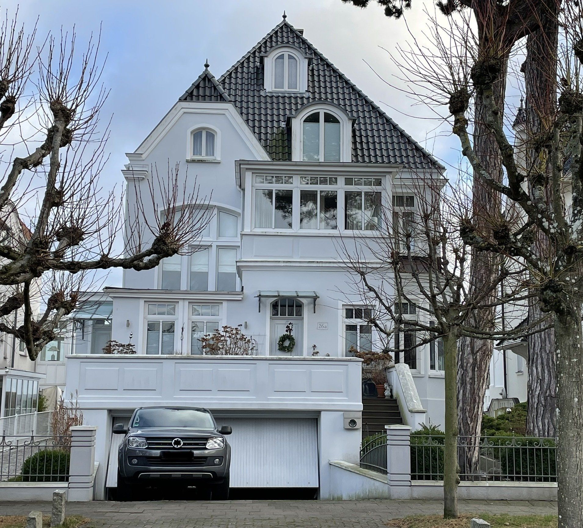 Ein Auto parkt vor einem großen weißen Haus