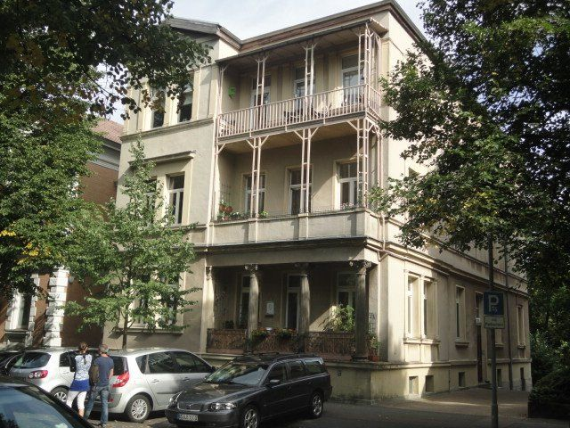 Ein großes weißes Gebäude mit davor geparkten Autos