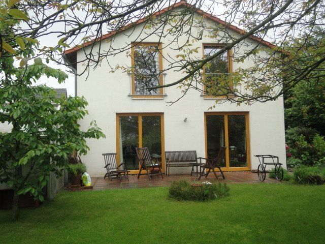 Ein weißes Haus mit rotem Dach steht inmitten eines üppigen grünen Hofes