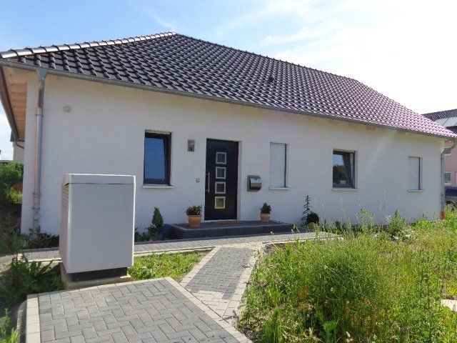 Ein weißes Haus mit einem violetten Dach und einer schwarzen Tür