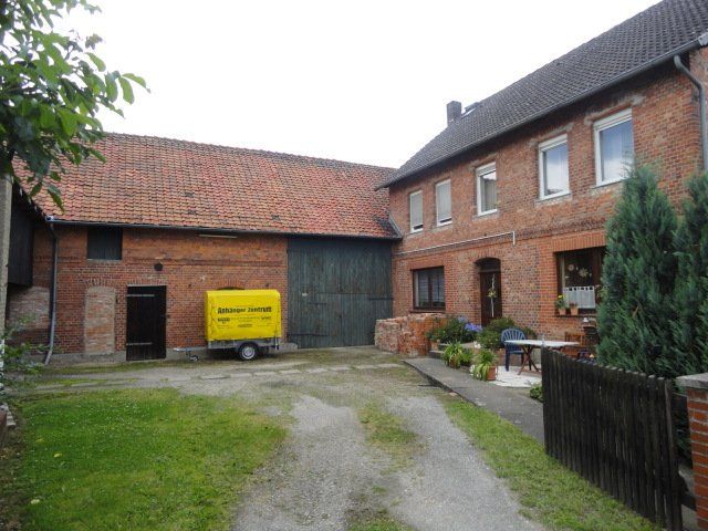 Ein gelber Anhänger steht vor einem Backsteingebäude