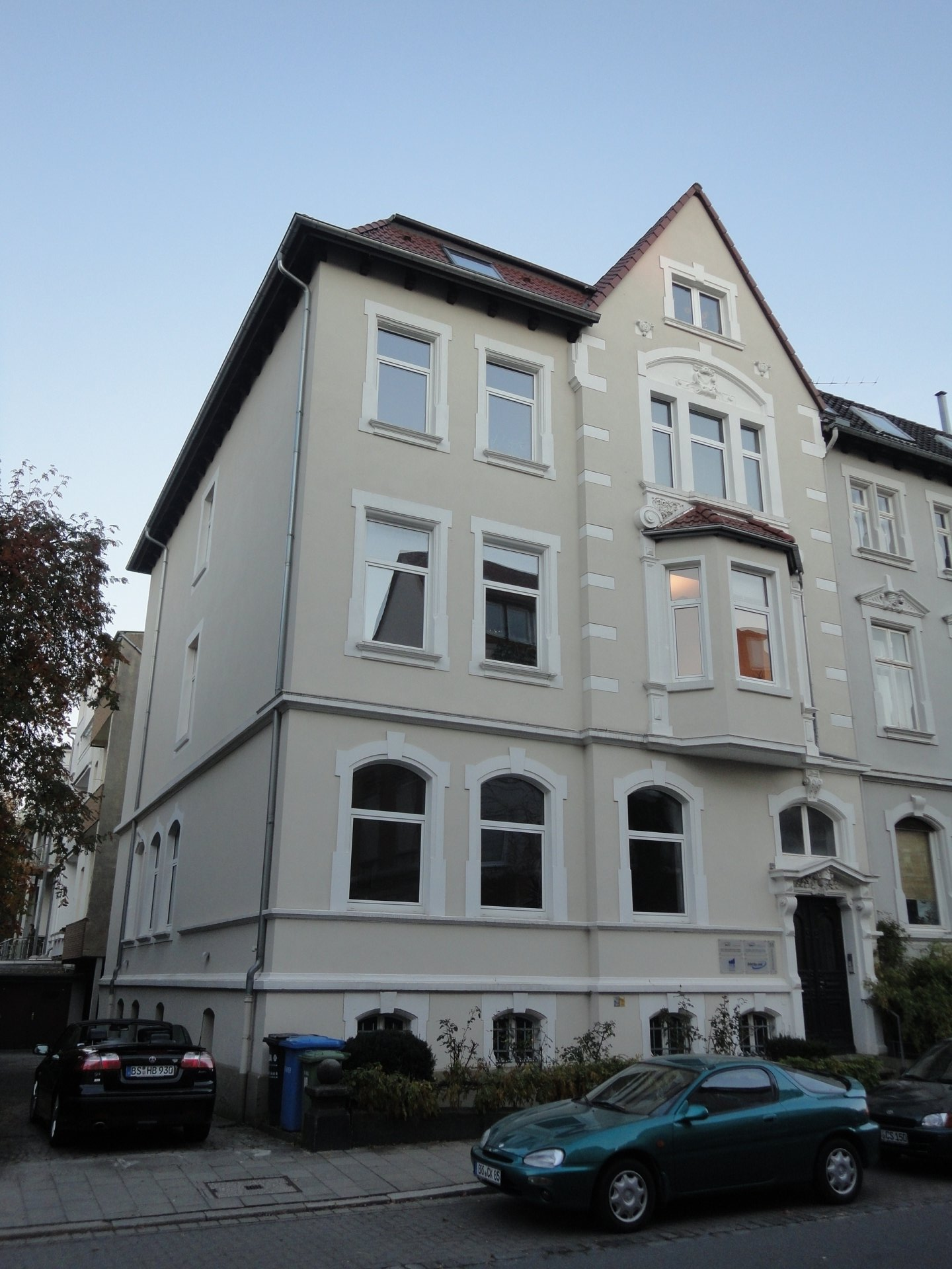 Ein grünes Auto parkt vor einem großen weißen Gebäude