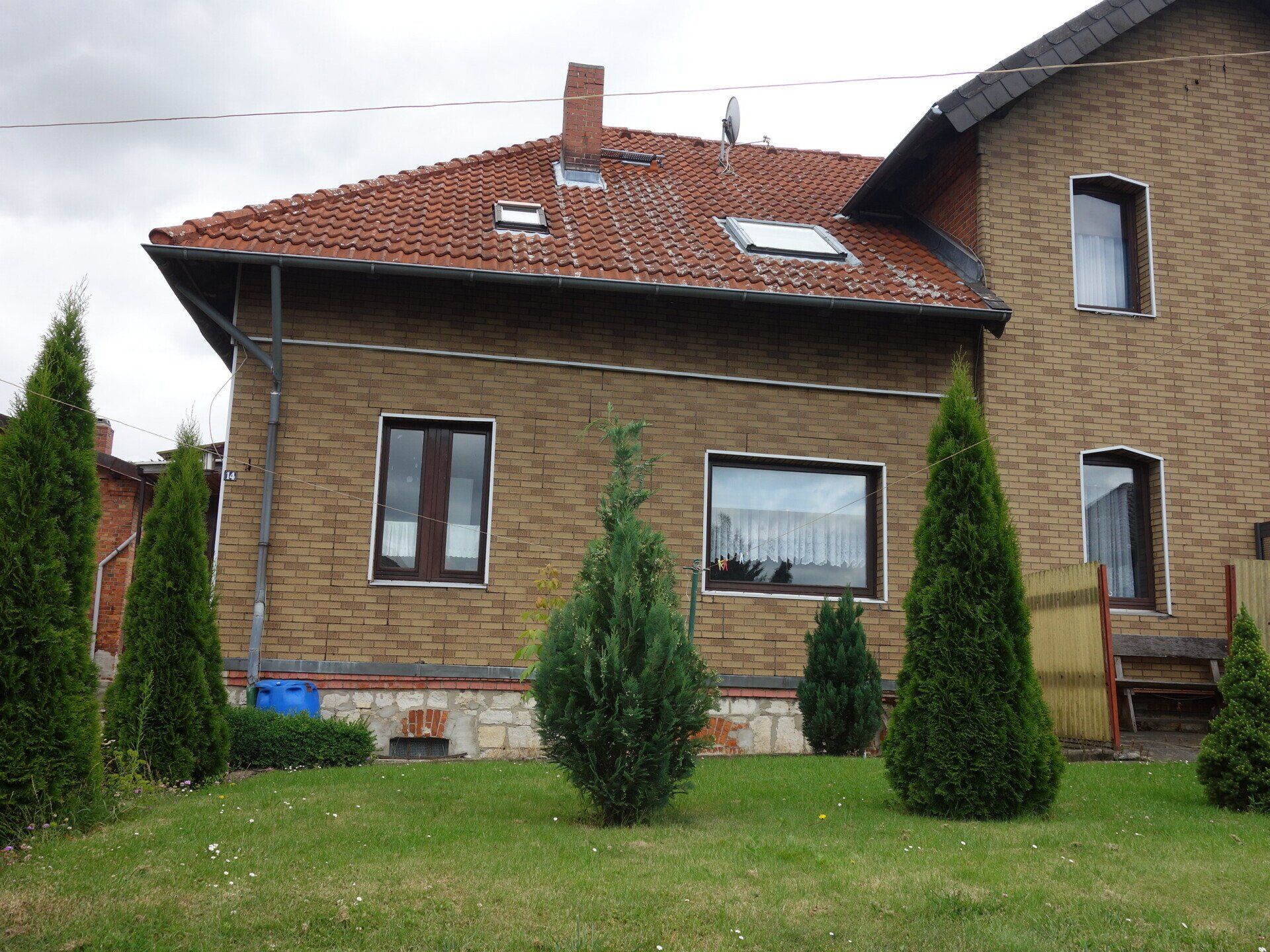 Ein Backsteinhaus mit einem roten Ziegeldach und Bäumen davor