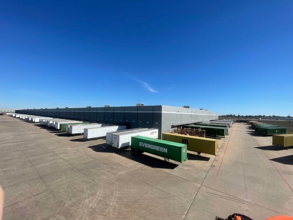 Large warehouse with docked trailers under a clear blue sky.