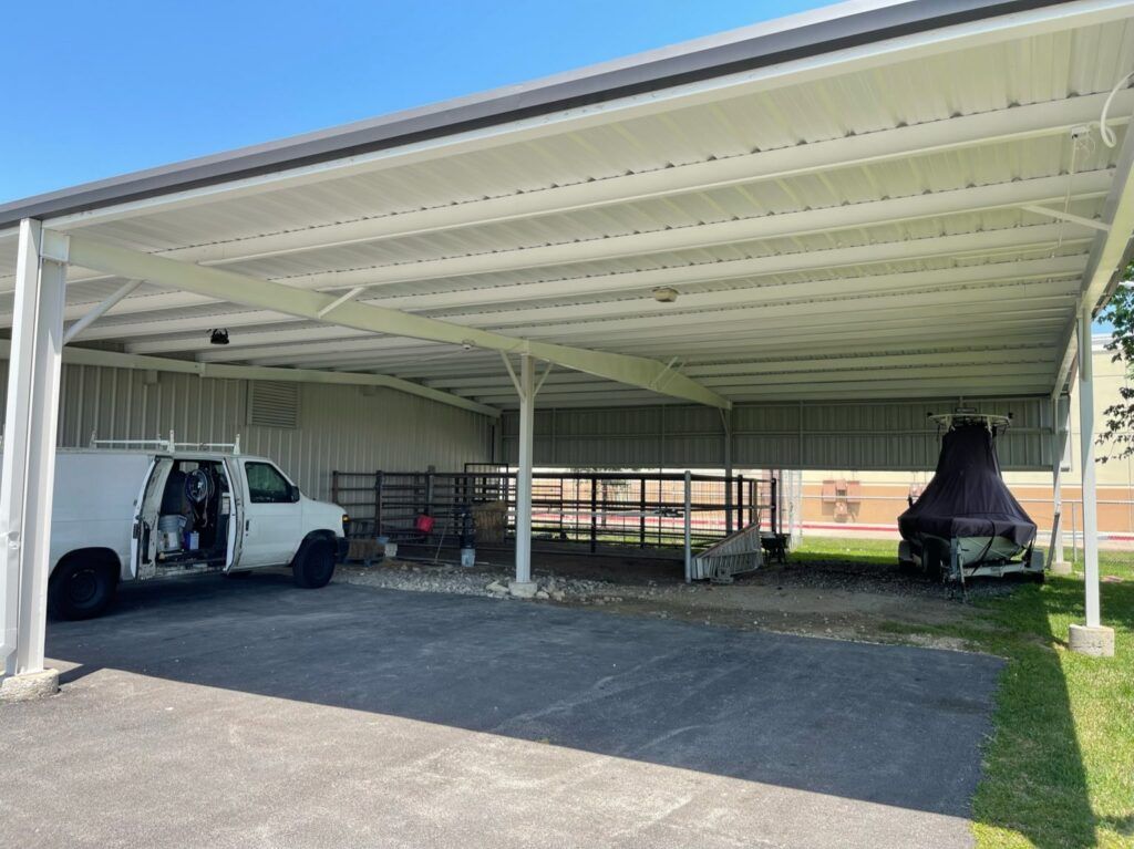 White carport with a truck parked underneath and a fenced area for animals.