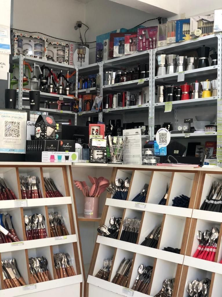 Interior de una tienda que muestra utensilios de cocina y cubiertos en estantes y expositores.