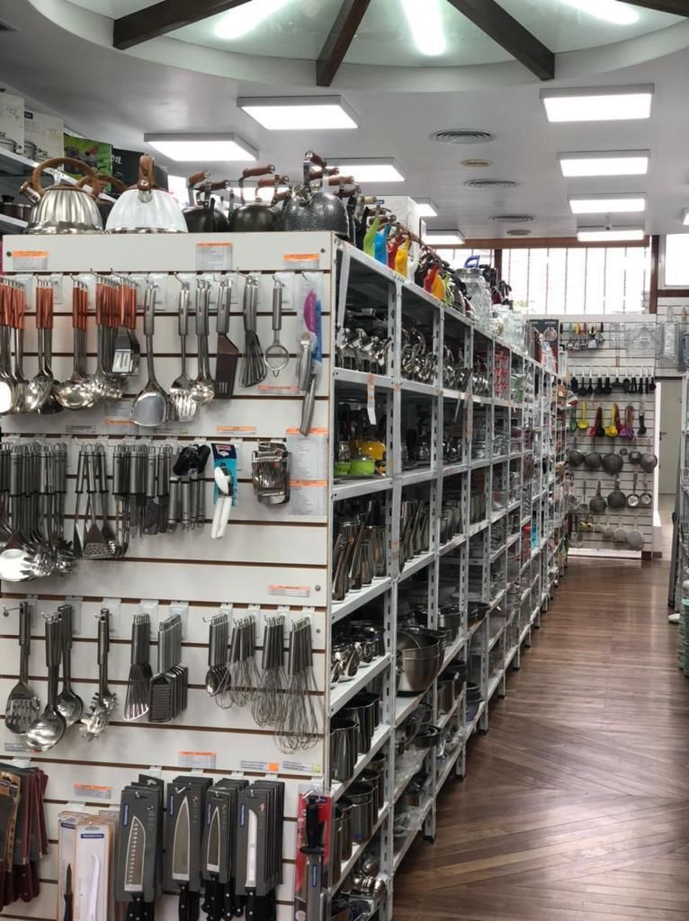 Utensilios de cocina exhibidos en el pasillo de una tienda con estantes de utensilios de cocina.
