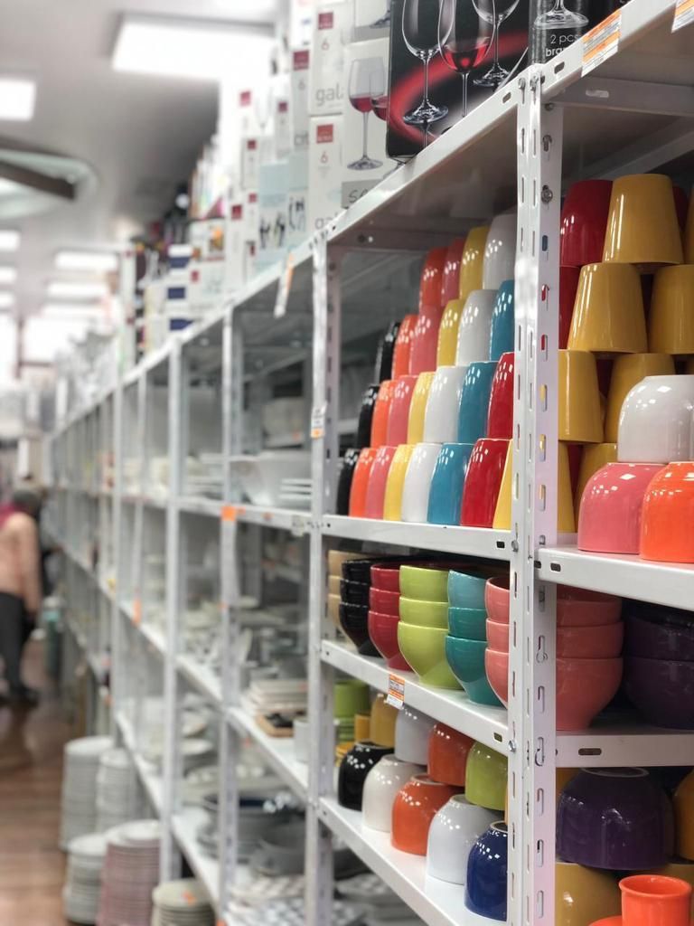 Estantes llenos de cuencos y tazas de colores en una tienda minorista.