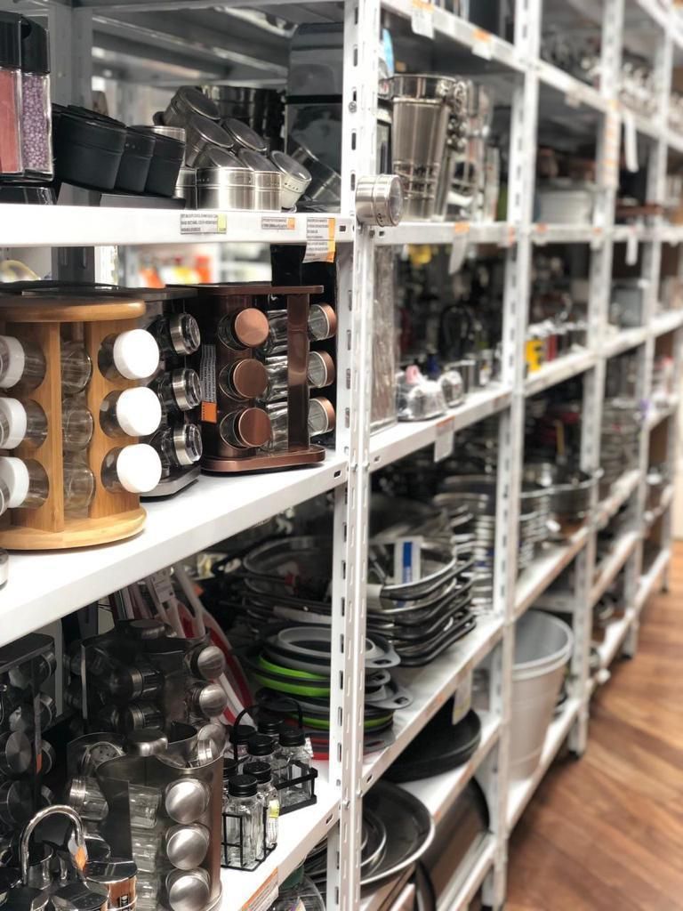 Estantes de una tienda llenos de utensilios de cocina, incluidos estantes para especias, ollas y utensilios.