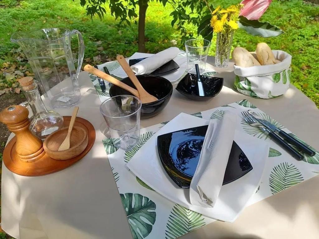 Mesa al aire libre con vajilla, utensilios, pan y flores.