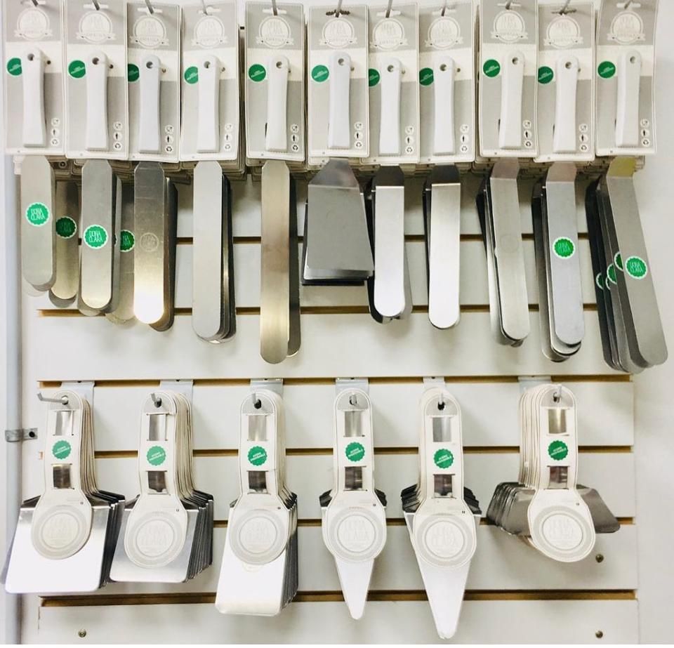 Varias espátulas y raspadores de cocina exhibidos en una pared blanca con empaques de productos.