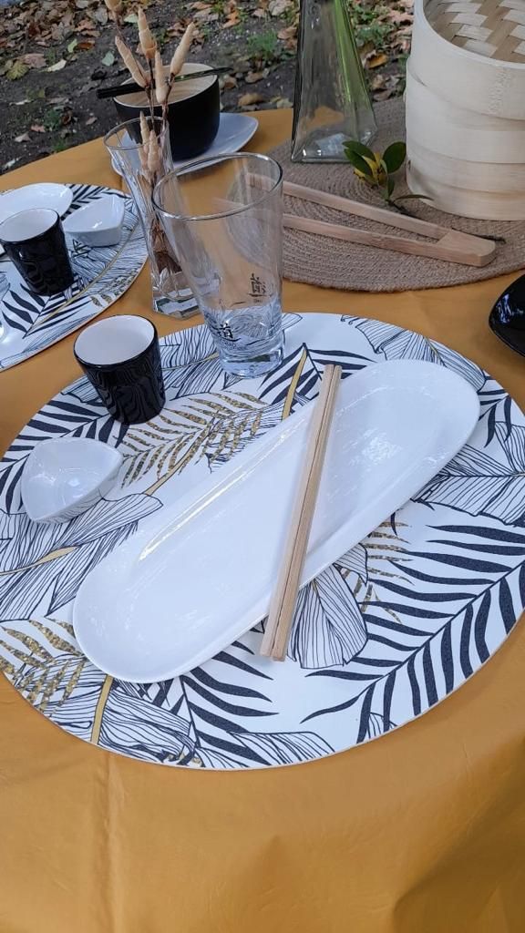 Mesa con manteles individuales blancos y negros de temática tropical