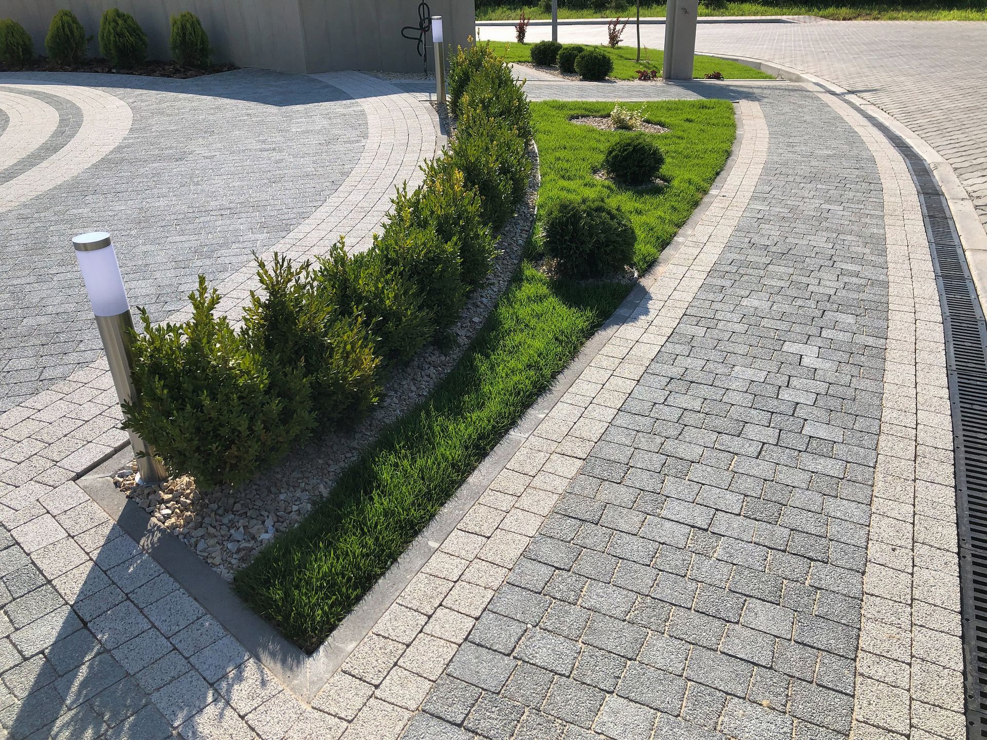 A brick walkway leading to a driveway with a truck parked in the background.