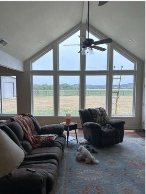 A living room with a lot of windows and a ceiling fan