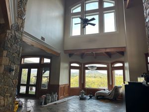 A living room with a lot of windows and a ceiling fan.