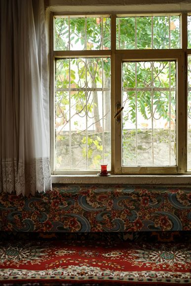 A room with a rug and a window with bars on it.