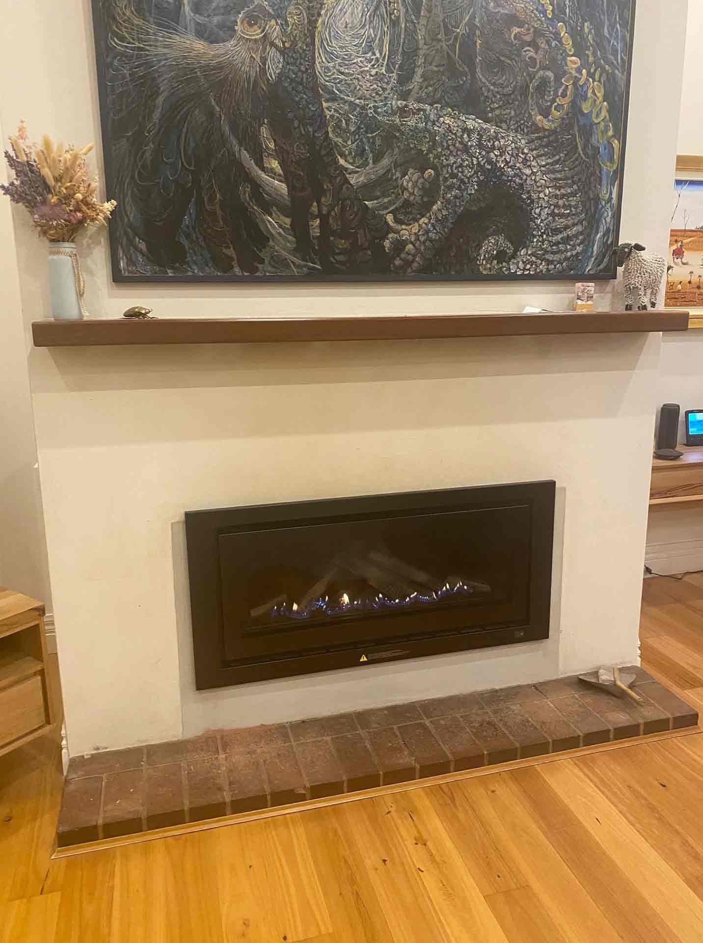 A Fireplace In A Living Room With A Painting On The Wall Above It — PalmAir Heating & Cooling Specialists In Tumbarumba, NSW