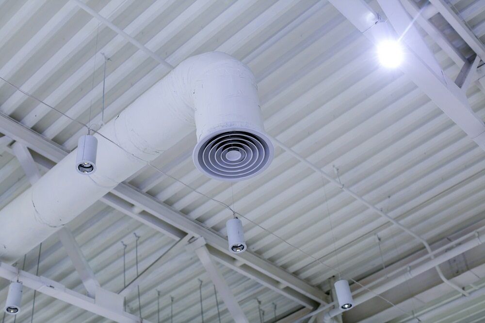 A White Air Duct Is Hanging From The Ceiling Of A Building — PalmAir Heating & Cooling Specialists In Tumut, NSW