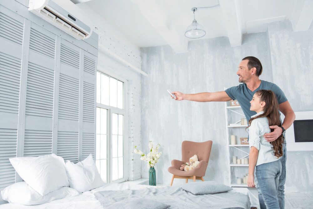 Father & Daughter In A Living Room Adjusting Air Conditioning Unit — PalmAir Heating & Cooling Specialists In Wagga Wagga, NSW