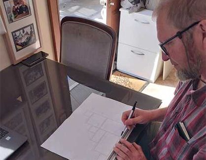 A man is sitting at a table writing on a piece of paper.