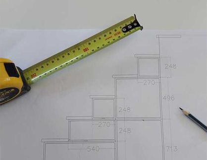A tape measure is sitting on top of a drawing of stairs.