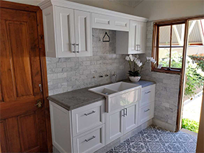 A man with a beard is standing with his arms crossed and smiling.