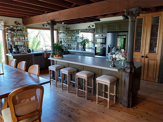 A kitchen with a long table and stools and a large island.