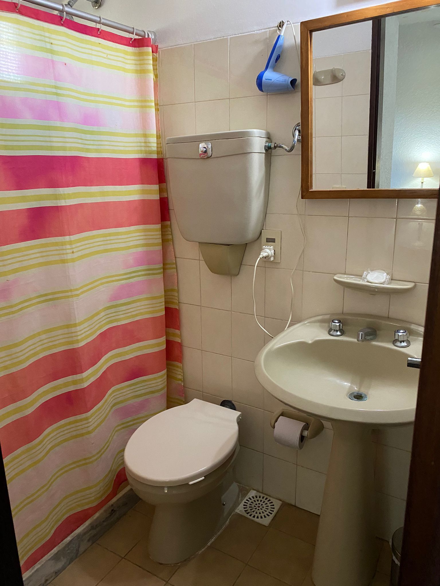 Baño pequeño con inodoro, lavabo, cortina de ducha y espejo.